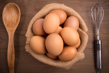 Fresh farm eggs on a wooden rustic background, Whipping eggs and whisk,top view with copy space