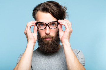 bearded hipster guy fixing his cat eye glasses. stylish modern fashionist. portrait of a geeky...