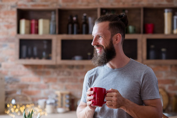 hot drinks and good or bad habits concept. happy smiling bearded man standing in the kitchen and...