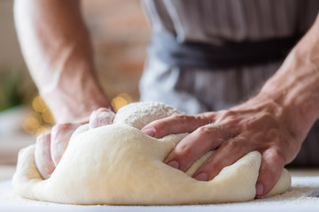 breadmaking recipe. food preparing and culinary skills concept. man hands kneading dough.