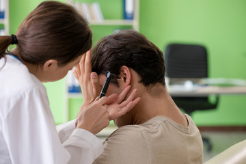 Female doctor checking patient's ear during medical examination 