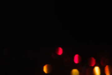 abstract lens flare on black background. pink and orange defocused bokeh lights. blurred christmas wallpaper decor. festive glowing circles design.