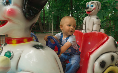Boy two years old verry happy, smiling, sits in toy car and driving