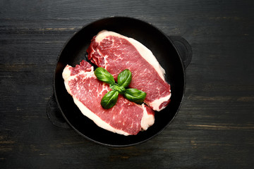 fresh raw marble beef in a frying pan on a wooden background.Top view.