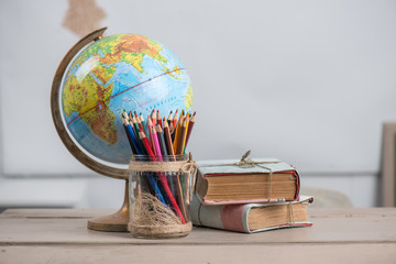 School background, books, globe and color pencils are on the desk
