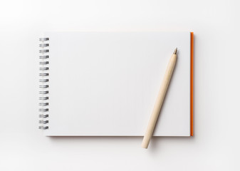 Top view of orange spiral notebook and pencil