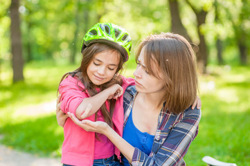 Little girl shows mother wound on elbow after falling from bicycle