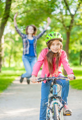 happy mother rejoices that her daughter learned to ride a bike