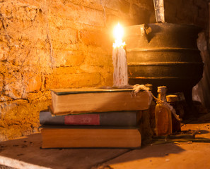 spell of witch night with candles and pot with fire between cobwebs and ancient earth