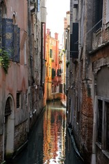 Obraz na płótnie Canvas Canale navigabile nella città turistica di Venezia con abitazioni e riflesso nell'acqua