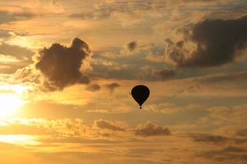 Balloons fly in the evening against the backdrop of the setting sun with clouds