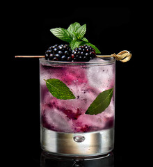 blackberry cocktail isolated on a black background decorated with mint