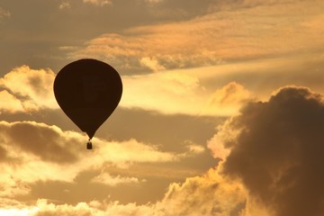 Balloons fly in the evening against the backdrop of the setting sun with clouds
