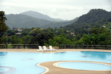 The outdoor swimming pool is in a natural setting with a mountain backdrop.