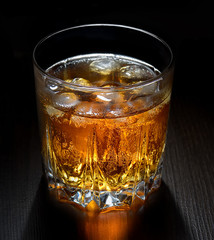 Glass of whiskey with ice on black background