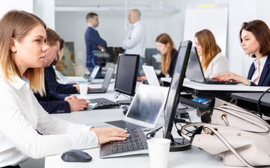 Young businesswoman concentrated on work with laptop in coworkin