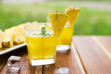 Pineapple fruits drink on wooden background.