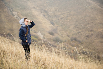 healthy school age girl looking far wearing jacket with hood in autumn mountains