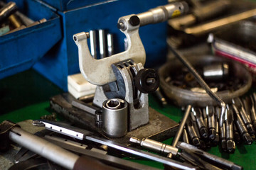 Micrometer and other tools for drilling and cutting metal lie on the table, close-up, manufacturing
