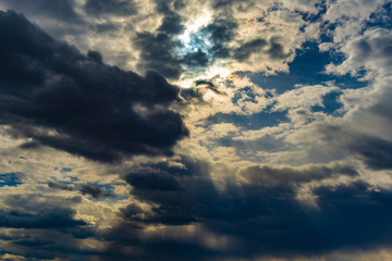 Obraz premium Abstract natural background. Dark and light clouds with the breaking rays of the sun in the evening sky.