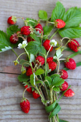 Obraz na płótnie Canvas Bouquet of wild strawberry with berries on wooden table