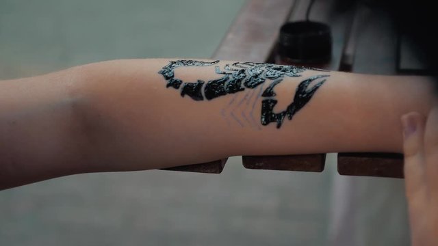 Drawing a child's tattoo on his hand with black paint. Beautiful drawing on a children's hand