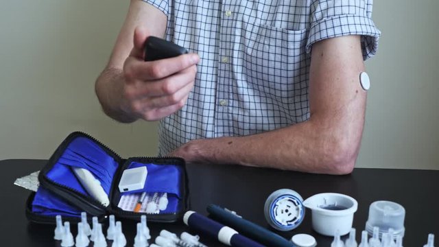A man brings to the hand the reading device to the sensor for measuring glucose
