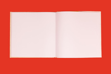 opened notebook with white papers lying on a red background. concept of office stationary. free copyspace