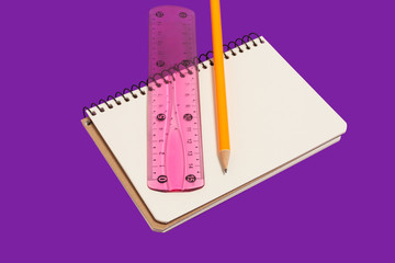 spiral opened notebook with pencil and ruler lying on a purple background. concept of office stationary. free copyspace