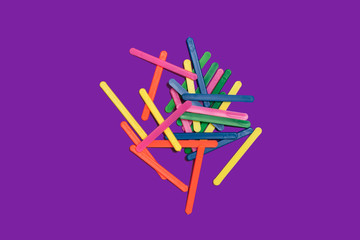 bunch of multicolored plastic counting sticks for children lying on a purple background. concept of mathematical operations. free space for advertising text
