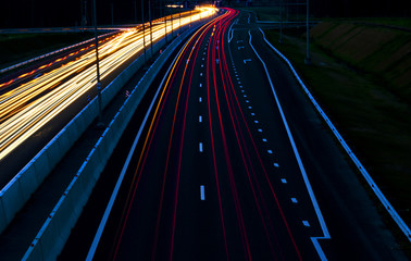 Fototapeta na wymiar Cars light trails on a curved highway at night. Night traffic trails. Motion blur. Night city road with traffic headlight motion. Cityscape. Light up road by vehicle motion blur.