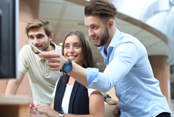 Group of young people in casual wear sitting at the office desk and discussing something while looking at PC together.