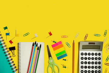 multiple school and office suplies and gadgets lying on a yellow background. free copyspace