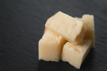 closeup cubes of parmesan cheese on slate board