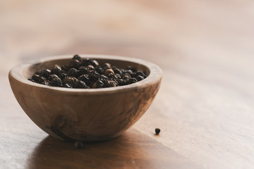 Fototapeta na wymiar black pepper in wood bowl on table