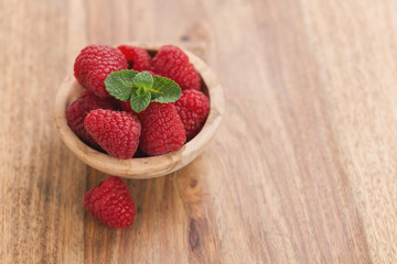 fresh raspberries in wood bowl on table with copy space