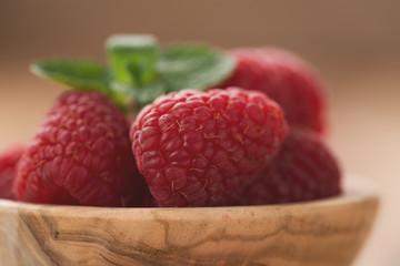 fresh raspberries in wood bowl on table