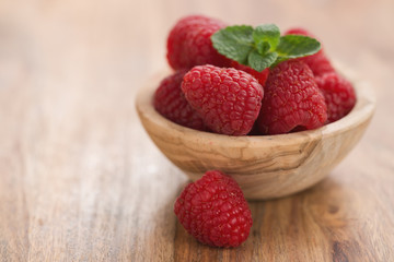 fresh raspberries in wood bowl on table with copy space