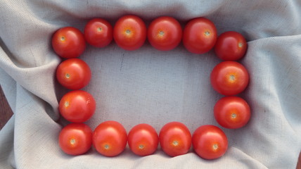 Fondo de textura de tela con marco de tomates mini rojos para poner tu texto en el centro