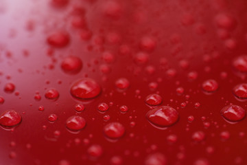 Closeup rain drops on red car with hydrophobic coating