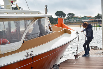 Obraz premium Young man tightens the ropes on the sails of the yacht. Sailing and recreation