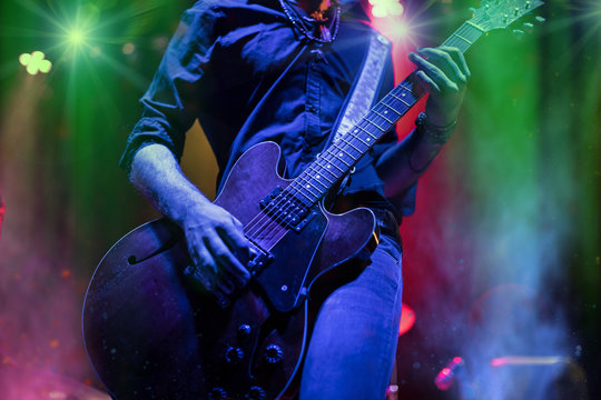 A rocker is playing guitar on stage.