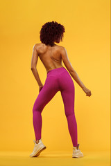 Fototapeta na wymiar Beautiful young and fit woman. Isolated on a yellow background in a pink sportswear