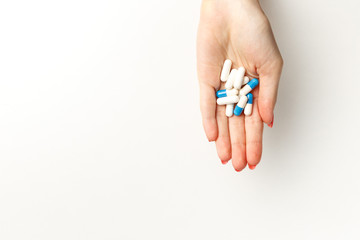 Colorful pills and tablets in the woman hand on white background. Top view. Flat lay. Copy space. Medicine concept