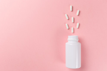 Assorted pharmaceutical medicine pills, tablets and capsules and bottle on pink background. Top view. Flat lay. Copy space. Medicine concept. Heap of pills on pink background