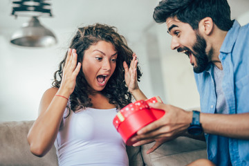 Man giving a surprise gift to woman at home