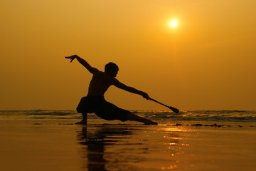 Fototapeta na wymiar silhouette of a man dancing alone on the beach. dance at sunset on Goa beach. northern Goa. India