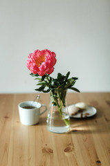  Vkusnyye zakuski mindal' i zefir na kukhonnom derevyannom stole ryadom s krasivym rozovym pionom  Delicious snacks of almonds and marshmallows on a wooden kitchen table next to a beautiful pink peony