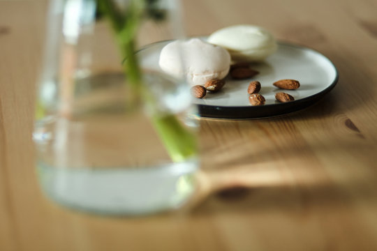  Vkusnyye zakuski mindal' i zefir na kukhonnom derevyannom stole ryadom s krasivym rozovym pionom  Delicious snacks of almonds and marshmallows on a wooden kitchen table next to a beautiful pink peony