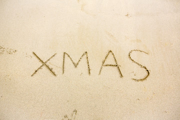 xmas hand writing on sand beach. christmas sign on natural brown background.celebrate christmas festival with the natural is concept. image for background, wallpaper.